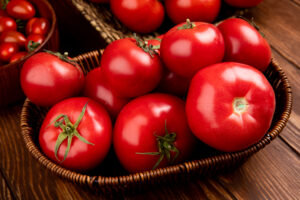 side view of tomatoes in basket on wooden background Tomatoes